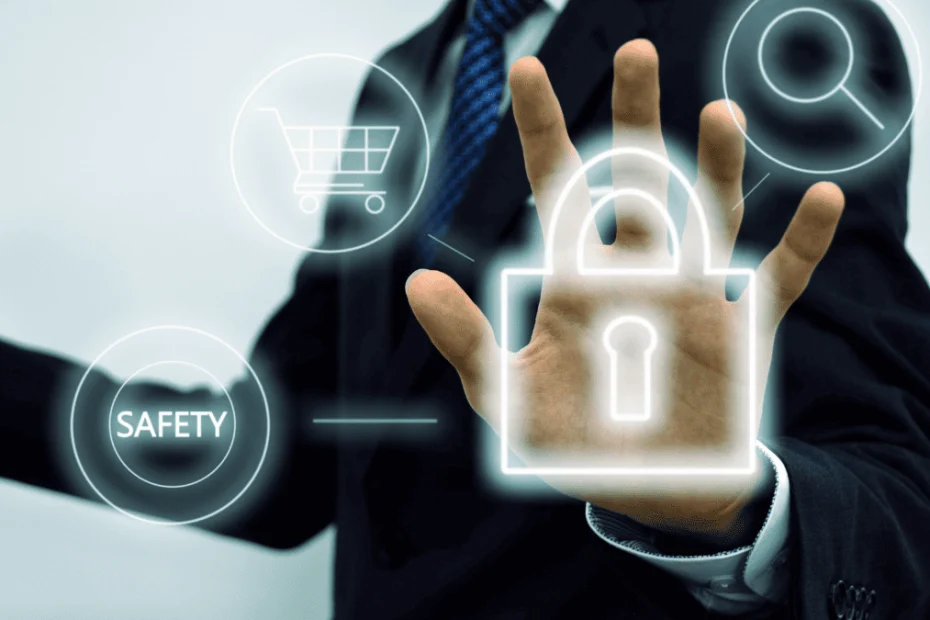 Hombre de negocios en traje interactúa con una interfaz digital donde se proyectan íconos como un candado, una lupa, un carrito de compras y la palabra “SAFETY”. Su mano abierta sobre el símbolo de un candado transmite la idea de protección. La imagen representa visualmente el concepto de cómo proteger una marca en entornos digitales, destacando la seguridad y la vigilancia como elementos clave.