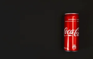 Lata de Coca-Cola de color rojo brillante con el logotipo blanco característico, colocada sobre un fondo negro liso. La imagen destaca la identidad visual reconocida globalmente de la marca Coca-Cola, lo que refuerza la importancia de proteger una marca en el extranjero frente a imitaciones o usos no autorizados.