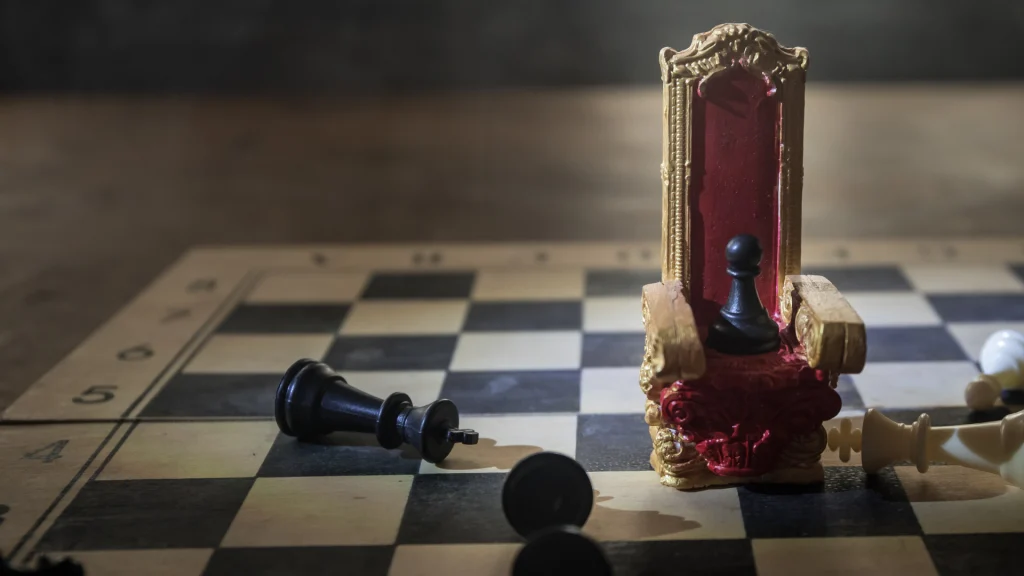 Peón negro en un trono dorado sobre un tablero de ajedrez con piezas caídas, simbolizando la lucha por el liderazgo en el mercado y los riesgos de la competencia desleal.