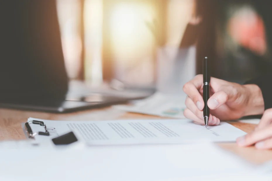 Persona firmando un contrato de prestación de servicios sobre una mesa de oficina