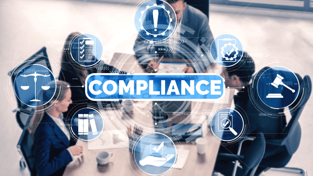 Imagen de un grupo de profesionales reunidos alrededor de una mesa de trabajo, vistos desde arriba, revisando documentos y usando dispositivos electrónicos. En el centro, se destaca la palabra “COMPLIANCE” (cumplimiento normativo) en letras grandes, rodeada por íconos digitales relacionados con el tema: una balanza de la justicia, un martillo de juez, una lista de verificación, engranajes con una marca de verificación, documentos legales, libros, una mano con una marca de aprobación y una lupa. La imagen transmite un entorno corporativo enfocado en la conformidad con normativas y estándares legales.