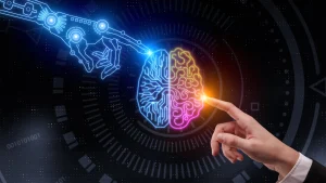 En el centro, un cerebro dividido en dos mitades: la izquierda, de color azul, con patrones de circuitos electrónicos que simbolizan la inteligencia artificial; la derecha, de color rosa y amarillo, con formas curvas que evocan la actividad cerebral humana. A la izquierda, una mano robótica azul se acerca al cerebro, mientras que a la derecha, una mano humana con el dedo índice extendido también lo toca. Ambas manos apuntan al centro del cerebro, simbolizando la interacción entre tecnología y mente humana en un entorno digital oscuro con elementos gráficos futuristas.