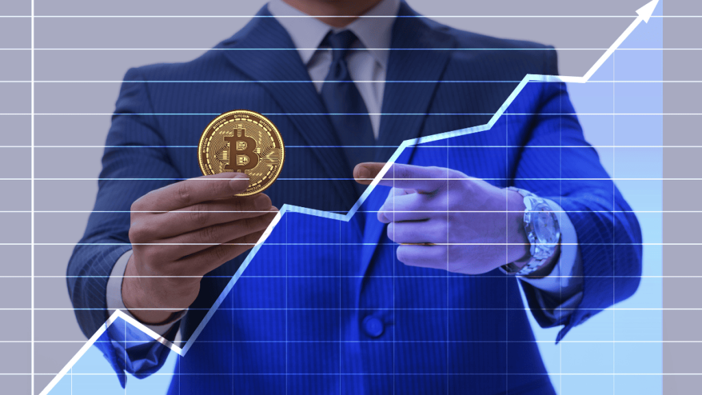 Hombre vestido con traje azul sosteniendo una moneda física de bitcoin con una mano, mientras señala con la otra. Al fondo, una gráfica financiera en tono azul con líneas ascendentes y flechas que representan el crecimiento del valor del bitcoin. La imagen transmite una idea de inversión y aumento en el mercado de las criptomonedas.