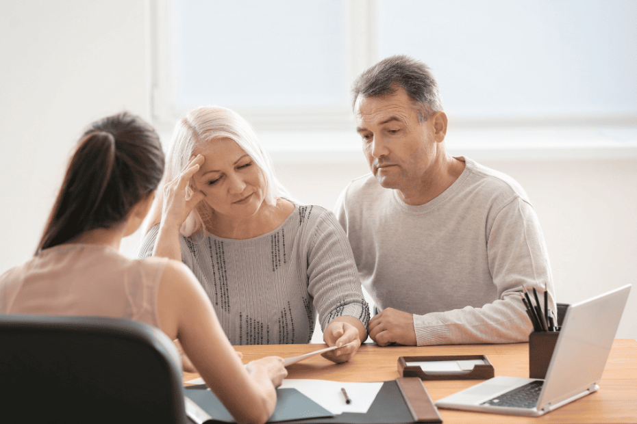 Pareja madura preocupada revisando documentos con una asesora legal en una oficina, representando las dificultades de las herencias internacionales y el uso del Certificado Sucesorio Europeo.