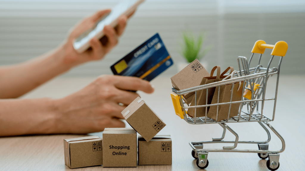 Carrito de compra con cajas de envío y una persona realizando una compra online con tarjeta de crédito, representando la reventa internacional y el comercio electrónico global.