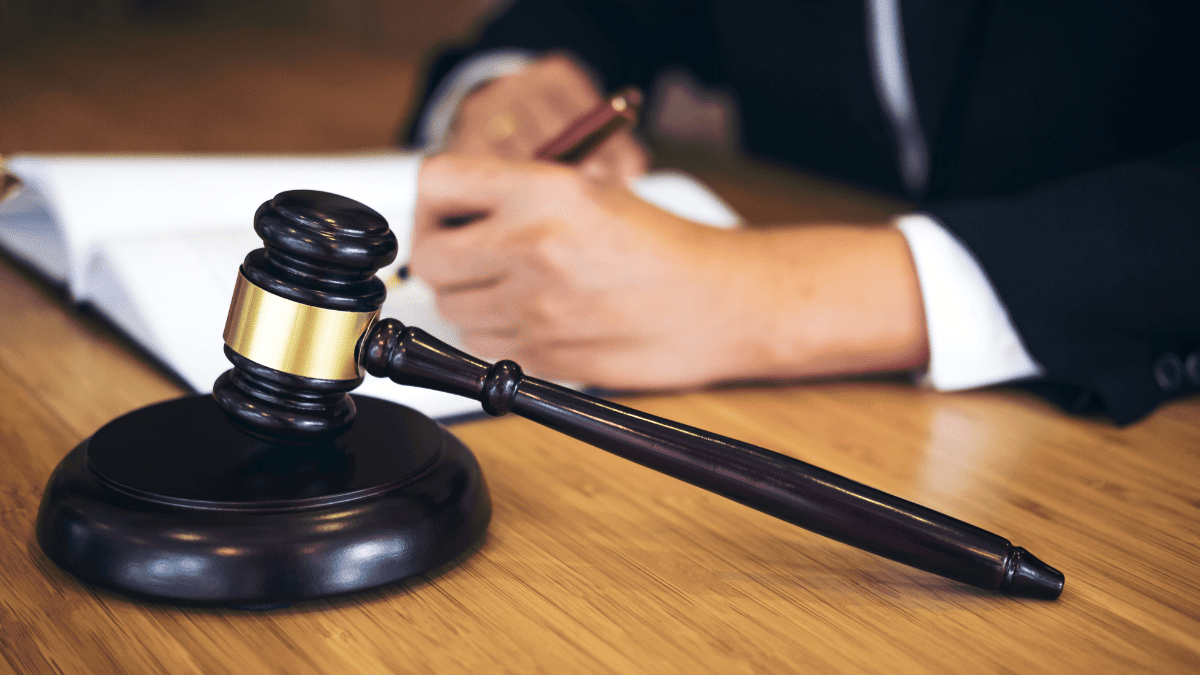 Mazo de juez sobre mesa y abogado redactando documentación de herencia internacional en la Unión Europea relacionada con el Certificado Sucesorio Europeo.