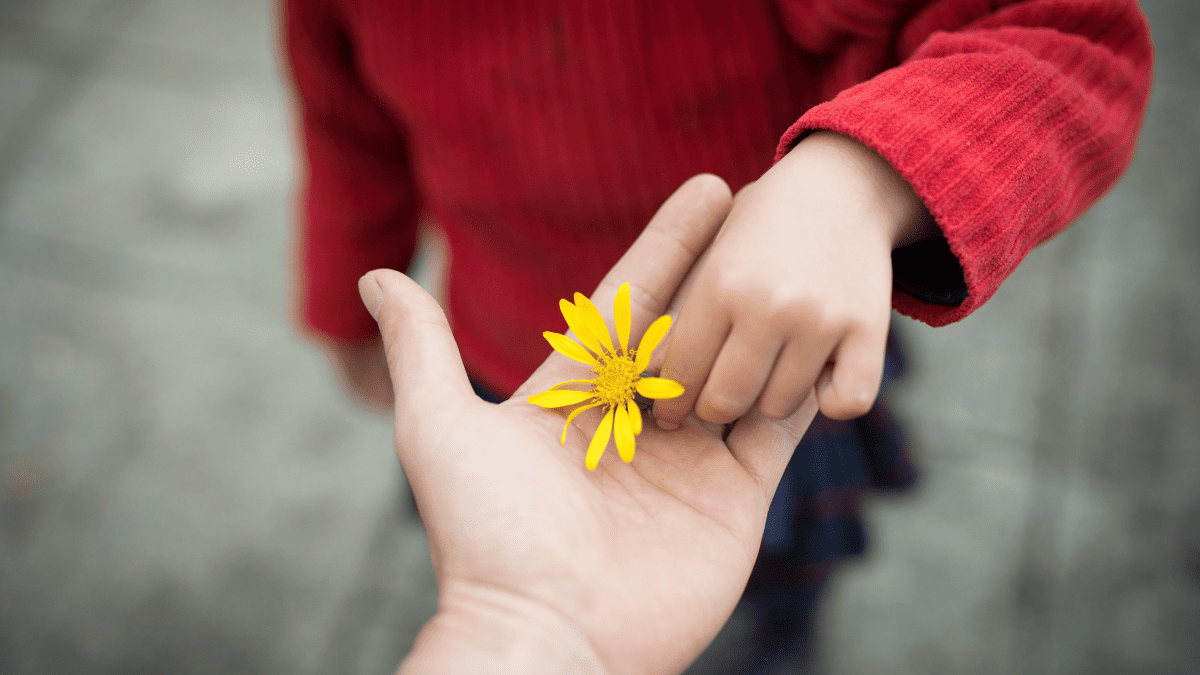 Niño entregando una flor amarilla a un adulto, simbolizando protección y vínculo familiar en casos de custodia internacional.