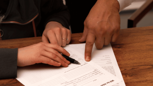 Manos señalando cláusulas en un documento legal con un bolígrafo, revisión para impugnar un testamento internacional.