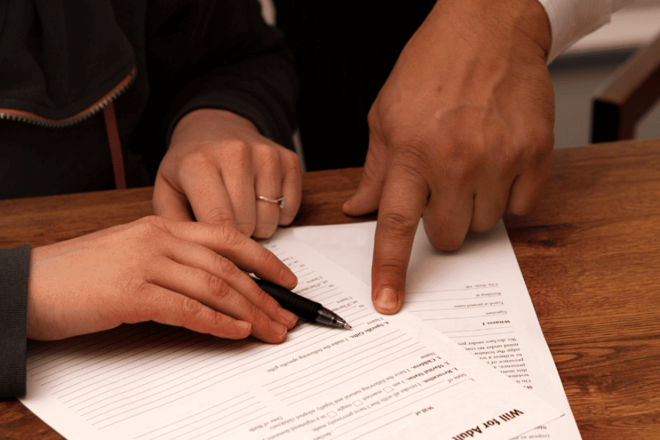 Manos señalando cláusulas en un documento legal con un bolígrafo, revisión para impugnar un testamento internacional.