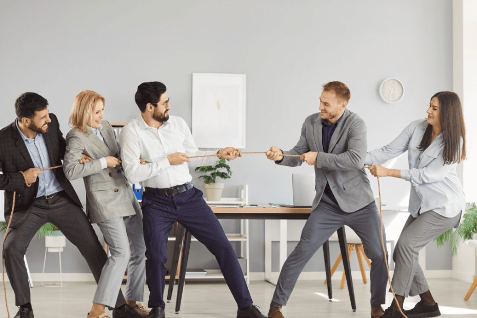 Equipo directivo en oficina tirando de una cuerda, representando conflicto entre ex socios o ex empleados y competencia desleal en empresa tecnológica.